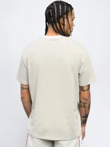 Remera color arena de corte clásico con cuello redondo ribeteado en blanco y logo Umbro estampado en el pecho.