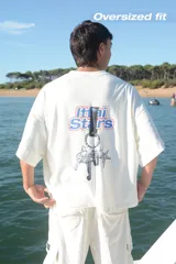 Camiseta celeste con estampado frontal de la frase "Ittai Stars" y una estrella. En la parte posterior tiene un estampado de un llavero con llaves y dijes.