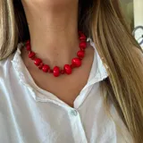 Collar corto de cuentas rojas de diferentes tamaños y formas, con cierre ajustable.