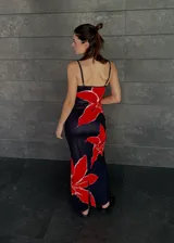 Vestido largo negro con estampado de flores rojas, de breteles finos y corte al cuerpo.