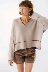 Sweater beige y azul con cuello en V y ribete bordeaux.