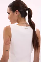 Chaleco tejido de punto color blanco, sin mangas, con escote en V y cierre frontal de botones dorados.