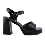Sandalias plateadas de tacón ancho y plataforma, con tira sobre los dedos y pulsera con hebilla al tobillo.