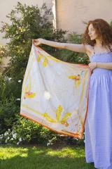 Pañuelo cuadrado de seda natural con estampado de flores amarillas y borde naranja.