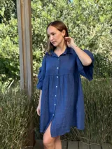 Vestido camisero azul de lino italiano, con cuello camisero, botones frontales, mangas 3/4 con doble volado y bolsillos laterales.