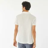 Remera blanca de punto gofrado con cuello polo y manga corta.