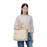 Bolso tote mediano de lona color crema con estampado de margaritas de colores. Tiene cierre superior con cremallera, asas superiores de lona resistente y correa de cincha ajustable y extraíble.
