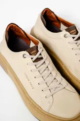 Zapatillas urbanas de cuero negro con cordones, suela blanca y detalles en marrón.