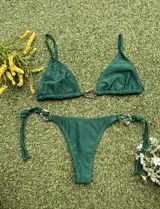 Conjunto de bikini verde con corpiño triangular con argolla metálica en el centro y bombacha colaless con tiras para atar y argollas en los costados.