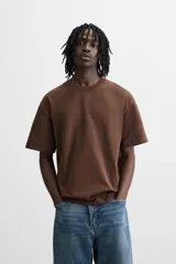 Camiseta blanca de algodón compacto, corte relaxed fit, cuello redondo y mangas cortas.