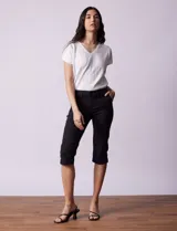 Pantalón capri blanco de algodón elastizado. Pretina con pasadores, botón y cierre. Delantera con bolsillos. Trasera con bolsillos simulados.