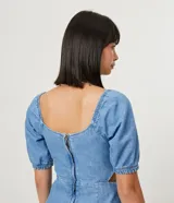 Vestido midi de jean celeste con escote en V, mangas cortas abullonadas, botones forrados en el frente, abertura frontal y corte en la cintura.