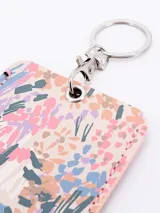 Llavero porta tarjeta rectangular con estampado floral en tonos pastel y herrajes plateados.