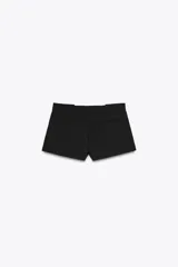 Shorts negros de tiro medio con cintura con trabillas y pliegues delanteros. Cierre frontal con cremallera, botón y ganchos metálicos.