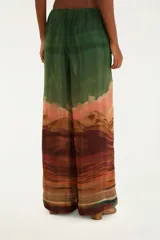 Pantalón palazzo con estampado de paisaje desértico en tonos verdes, marrones, naranjas y celestes. Presenta cintura alta con cordones ajustables.