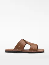 Sandalia plana color marrón con tiras de cuero entrelazadas y puntera cuadrada.