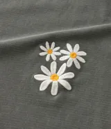 Blusa verde militar de algodón con cuello redondo y mangas cortas con dobladillo. Presenta un pequeño bordado de flores en el frente.