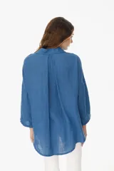 Camisa de lino blanca con cuello clásico, botonadura frontal y bolsillo en el pecho.