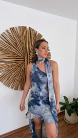 Vestido largo de fiesta con estampado tie-dye en tonos de azul y blanco. Presenta escote halter con lazos y abertura lateral en la falda.