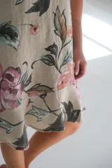 Vestido sin mangas color beige con estampado de flores rosas y hojas verdes.