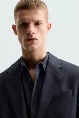 Blazer azul marino de lino con corte regular fit, cuello con solapas de muesca, manga larga con puños abotonados, bolsillo de vivo en el pecho, bolsillos de solapa en la cadera, bolsillo interior, aberturas en la espalda y cierre frontal de botonadura.