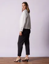 Chaqueta cruda de tejido boucle con flecos en el borde y botones negros en los puños.