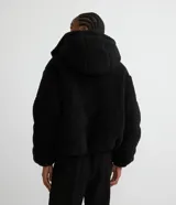 Campera puffer de sherpa color negro, con capucha, cierre frontal y regulador elástico en la cintura.
