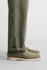 Mocasín casual de hombre color verde oliva, fabricado en cuero con acabado serraje, corte liso con detalle de bordón, horma redonda y suela a contraste color crema.
