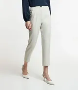 Pantalón zanahoria de sastrería color blanco, con cintura alta, trabillas y botón contrastante.