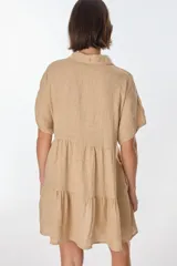 Vestido corto celeste de lino, con cuello tipo polo con detalle de puntilla, mangas cortas y falda escalonada con volantes.