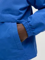 Campera azul de nylon con capucha, cierre frontal con cremallera, bolsillos delanteros y puños elásticos.