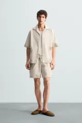 Bermuda regular fit color beige con bordados de flores en tono marrón. Tiene cintura elástica ajustable con cordón, bolsillos laterales y un bolsillo trasero de plastrón.