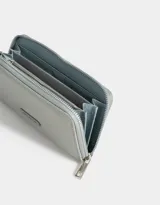 Billetera negra rectangular con cierre circundante y tag metálico con logo.