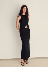 Vestido largo negro con chaleco incorporado, sin mangas y con abertura triangular en el abdomen.