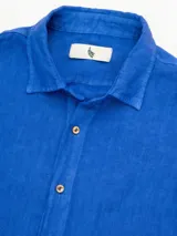 Camisa celeste de lino, de manga larga con botones de coco y parche de la marca.