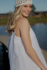 Vestido blanco de lino con breteles de cuero extraíbles mediante botón y ojal, corte suelto y tajos a los costados.