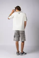 Remera tejida color crudo con cuello tipo chomba en V, mangas cortas con rayas negras y estampado con letras en el frente. Confeccionada en hilado de algodón.