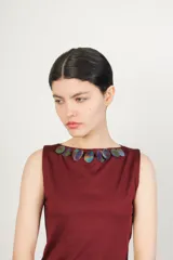 Top color borgoña, sin mangas, con escote bote decorado con lentejuelas iridiscentes.
