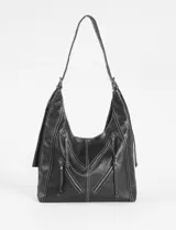 Cartera hobo color crudo de cuero sintético, con correa de hombro ajustable y múltiples cierres decorativos en el frente.