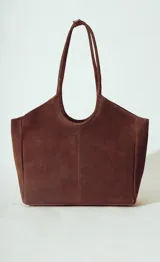 Bolso tipo tote bag de gamuza color marrón oscuro, con asas de hombro largas y estructura rectangular.