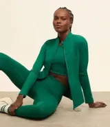 Campera deportiva verde esmeralda de microfibra con cierre frontal, cuello alto, bolsillos laterales y recortes en los hombros.
