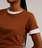 Blusa básica de algodón color tostado, de manga corta con dobladillo y nudo frontal.