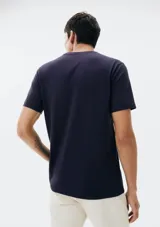 Camiseta color beige de manga corta con cuello redondo y parche con logo en el pecho.