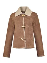 Chaqueta de gamulán de cuero color caramelo, con interior forrado en shearling. Presenta cuello clásico de borrego, cierre frontal con botones tipo toggle de madera y detalles de costura.