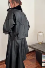 Campera bomber negra de cuero con cuello de piel sintética negra, forro interior y detalles de pasamanería en cuero marrón gastado en las mangas.