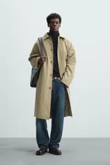 Gabardina color arena de corte amplio, con cuello solapa, manga larga, cierre frontal con botones y bolsillos laterales con solapa.