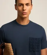 Remera azul marino de algodón, con cuello redondo y manga corta. Presenta un bolsillo delantero con detalles bordados.