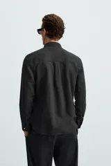 Camisa celeste a rayas verticales, de corte relaxed fit, confeccionada en lino y algodón. Tiene cuello abotonado, manga larga con puños abotonados, bolsillo de parche en el pecho y cierre frontal con botones.