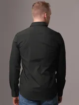 Camisa de vestir verde oscuro de popelín de algodón elástico, corte slim, con cierre frontal de botones y logo CK bordado en el pecho.