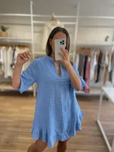 Vestido corto de lino 100% color celeste, con cuello mao y abertura en V. Presenta mangas cortas con detalle de volado y ruedo con volado.